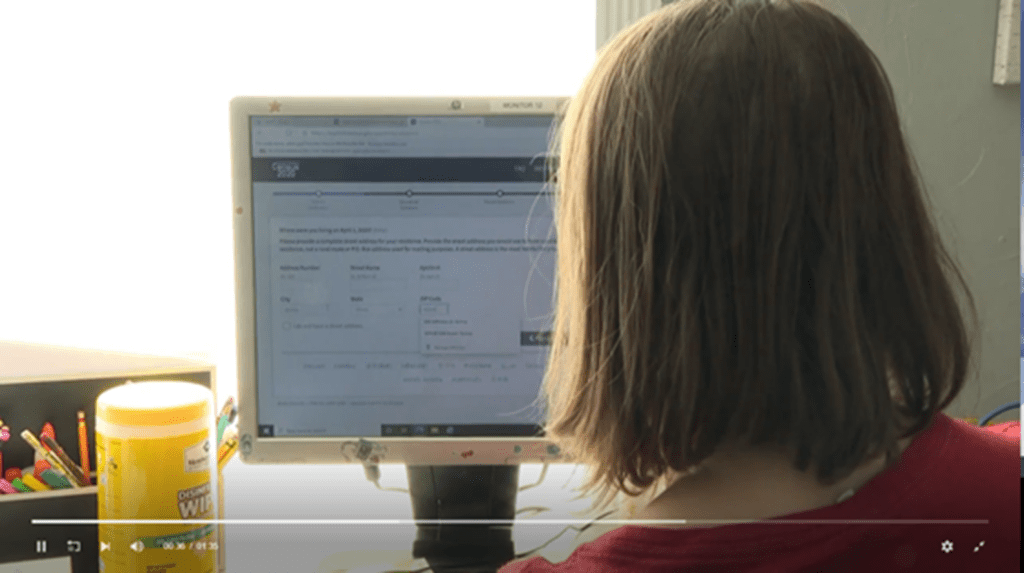 A person sitting in front of a computer screen.