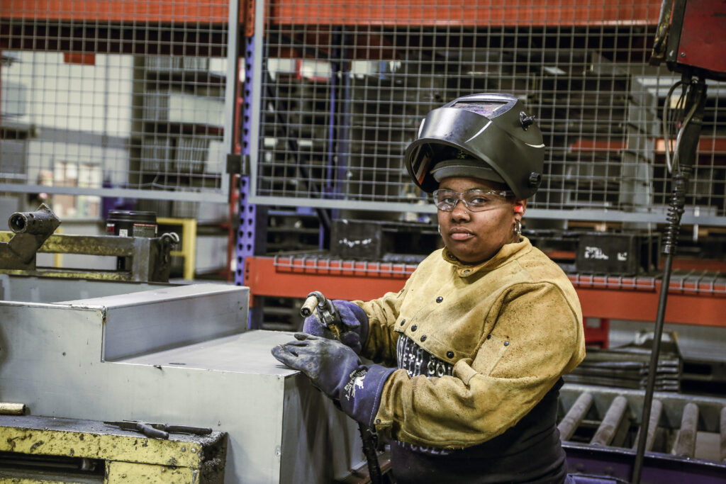 A woman wearing safety gear and welding gloves.