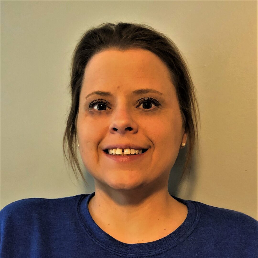 A woman with brown hair and blue shirt smiling.