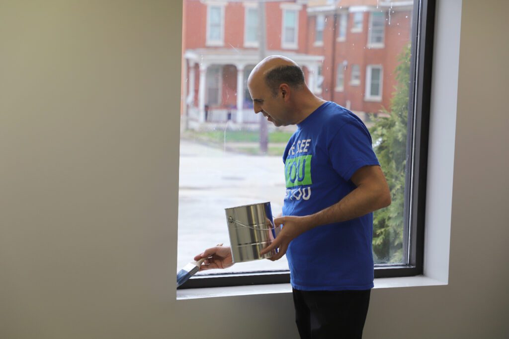 A man standing in front of a window holding onto some papers