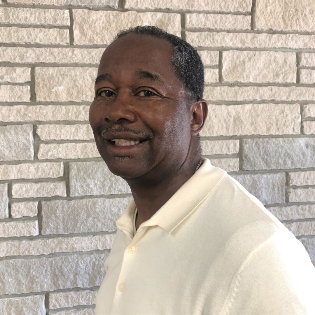 A man standing in front of a brick wall.